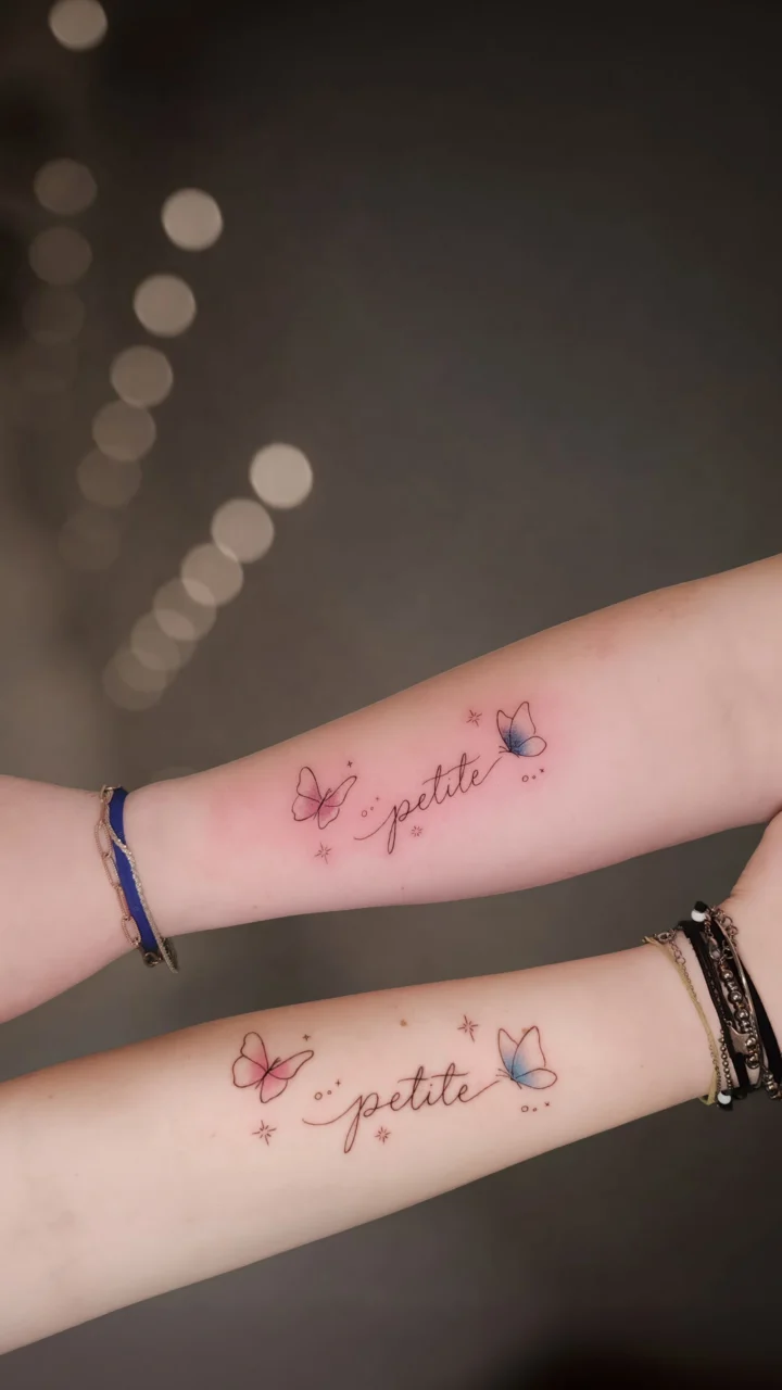 Tatuaggio in coppia su due avambracci: la scritta «petite» in corsivo tra farfalle rosa e azzurre e piccole stelle.